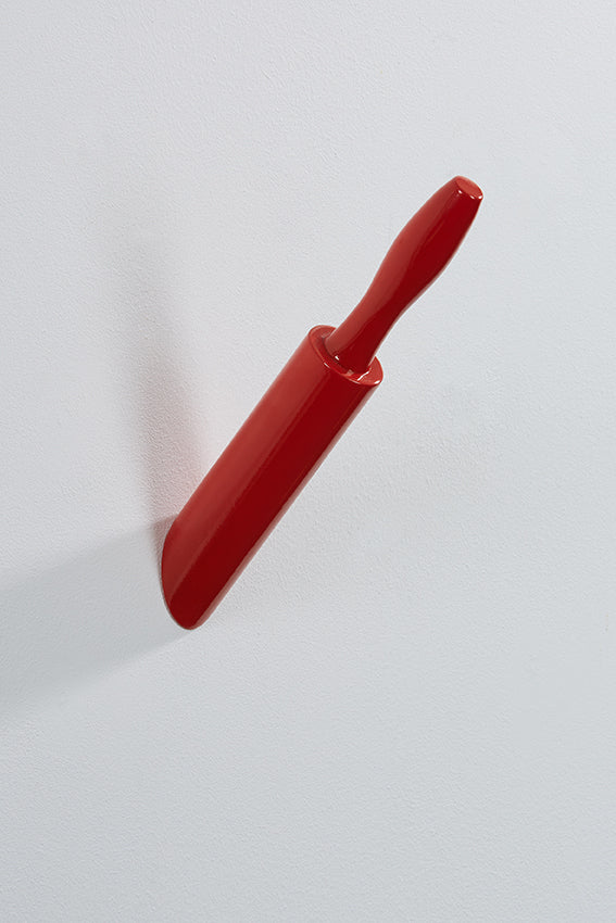 A wall hook shaped like a rolling pin appears embedded in the wall, red colour.