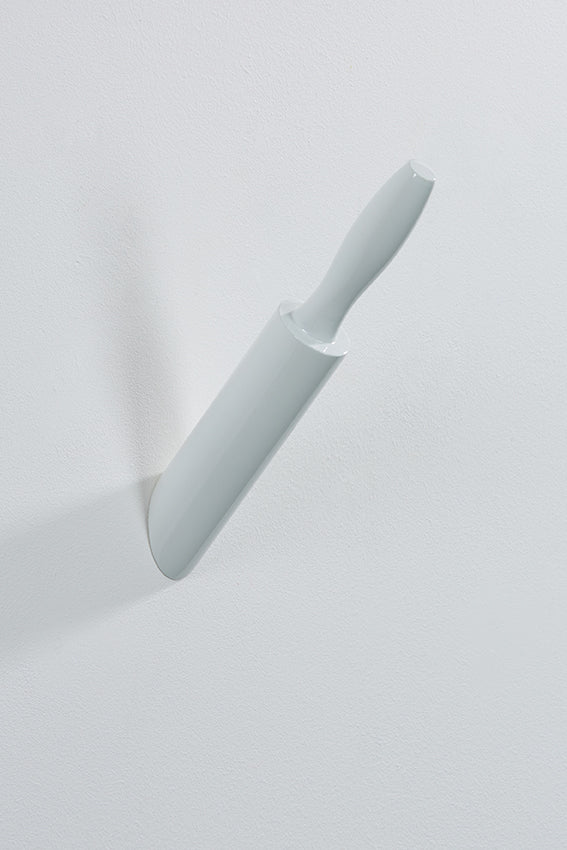 A white wall hook shaped like a rolling pin appears embedded in the wall.